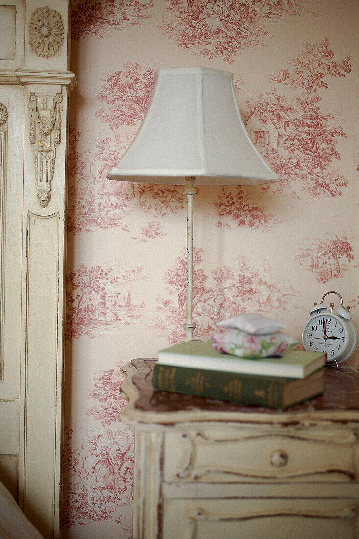 Lampe auf dem Nachttisch mit Büchern und Wecker