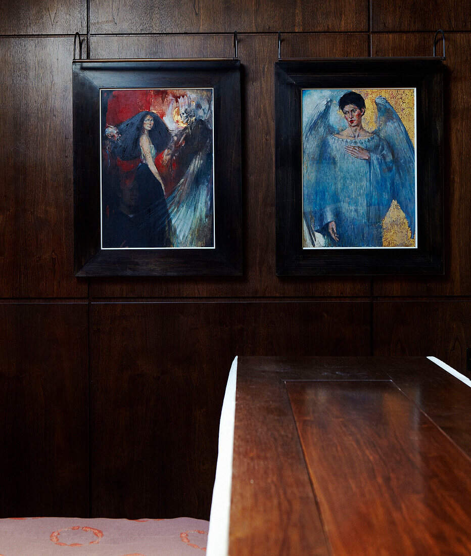Modern art depicting a demon and angel hangs on wood panelled wall