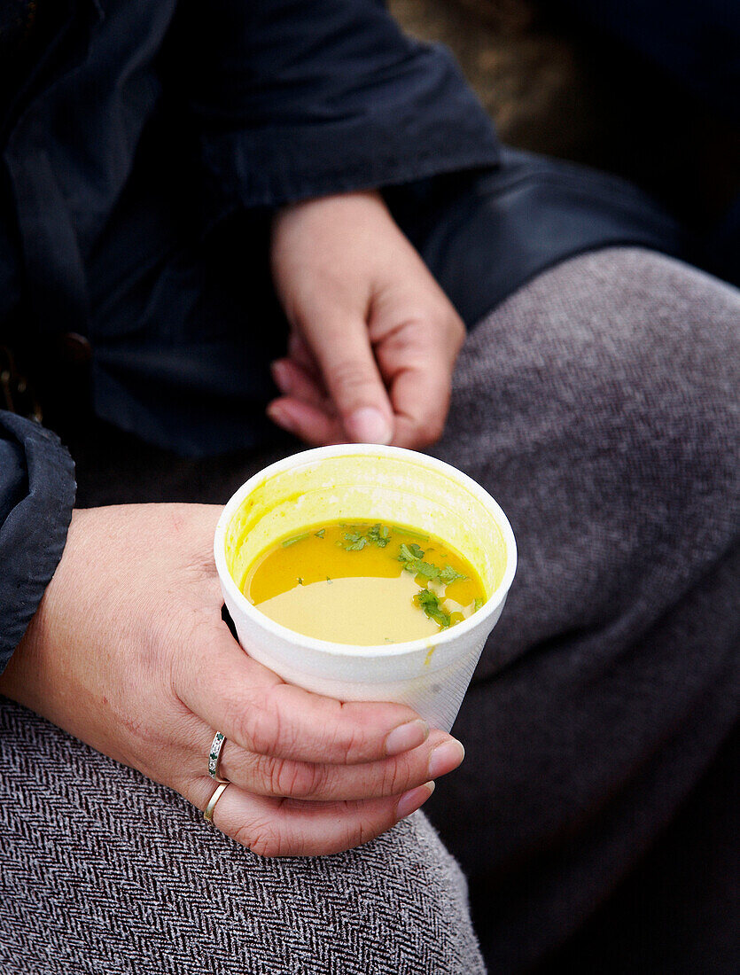 Frau sitzt mit einer Tasse Suppe in der Hand