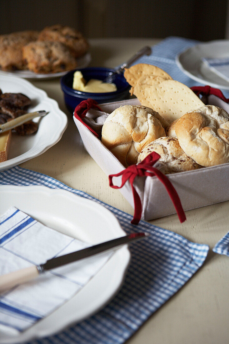 Breadbins and butter on table set with gingham placemats