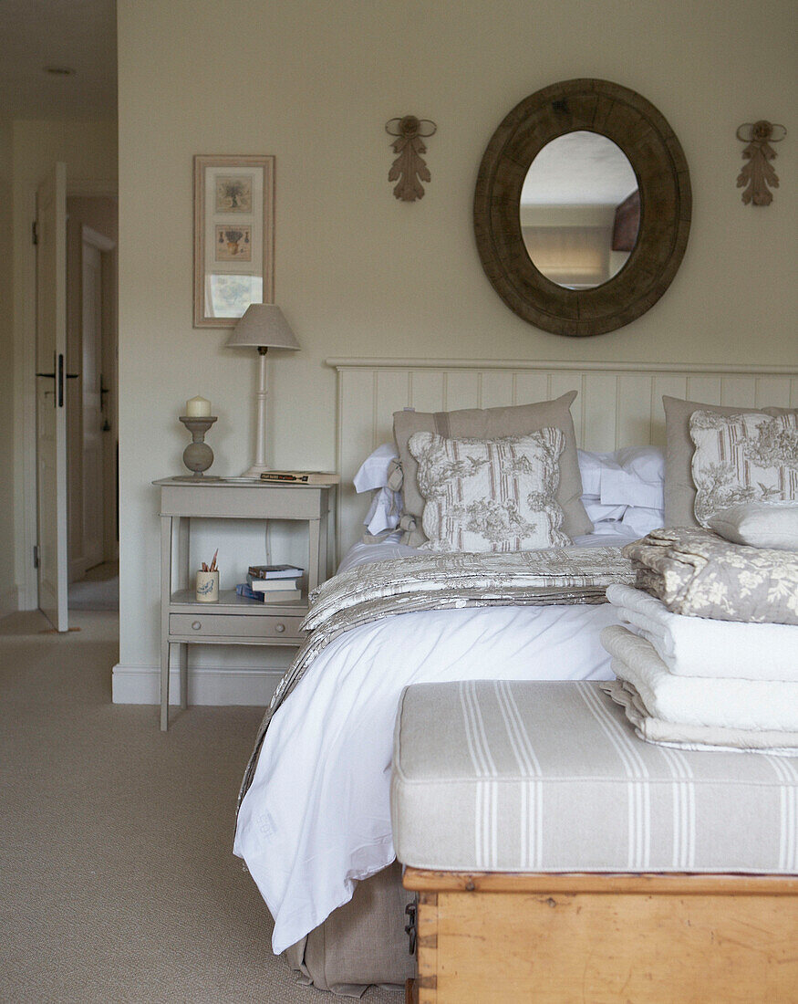 Circular mirror above double bed with metal headboard