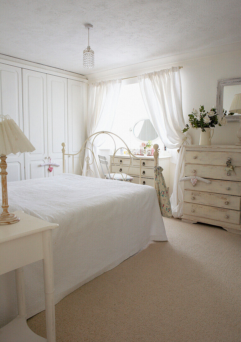 Weißes Schlafzimmer im Landhausstil mit Einbauschränken und einem sonnendurchfluteten Fenster