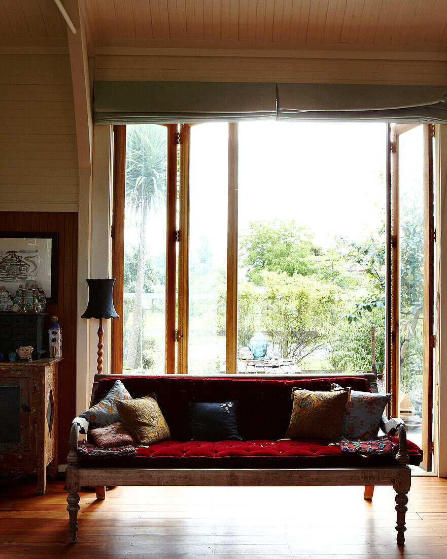Nicht zusammenpassende Kissen auf dem Sofa im sonnenbeschienenen Eingangsbereich eines Hauses in Masterton, Neuseeland