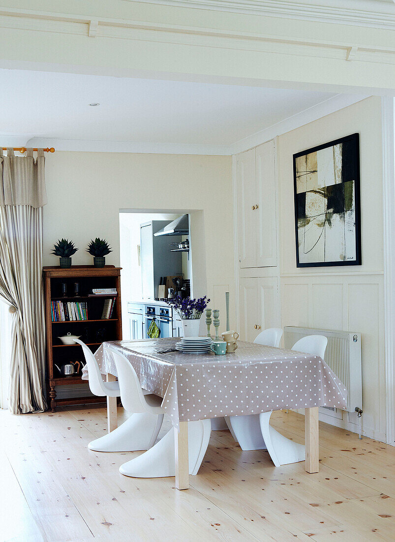 Open plan dining room with spotted tablecloth and wooden floor