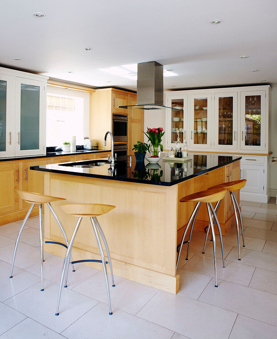 Wooden bar stools at kitchen island with black shiny worktop