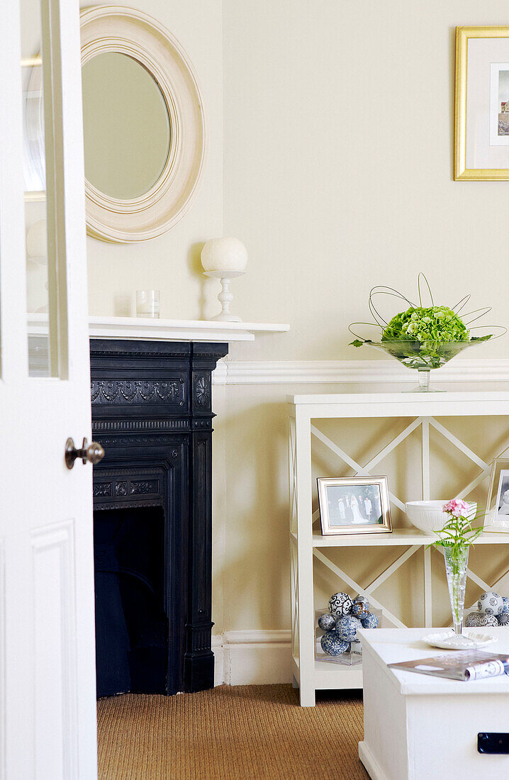 View through doorway to cream living room with original fireplace and shelving