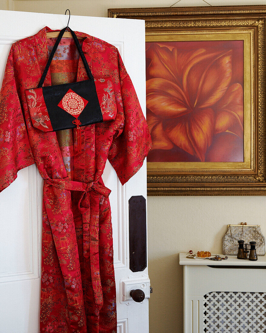 Bright red silk dressing gown hanging on the back of a panel door