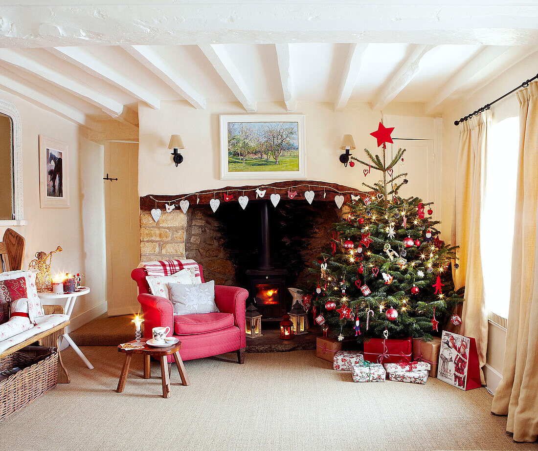 Christmas tree and red armchair at open fireplace with heart shaped decorations