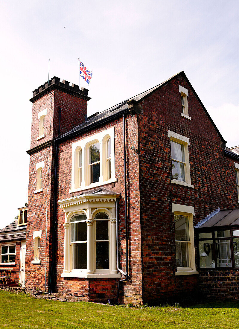 Brick exterior of country home with Union Jack flying from tower