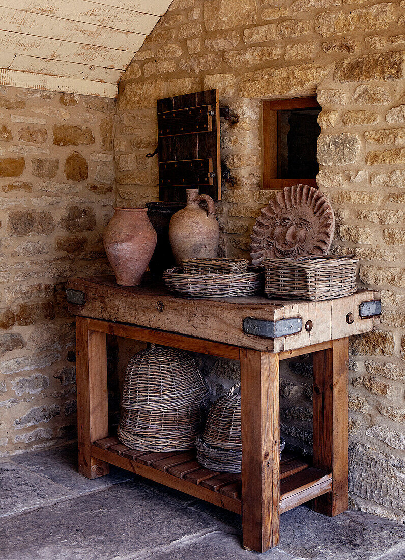 Korbstühle am Tisch in einem Außenraum eines steinernen Landhauses