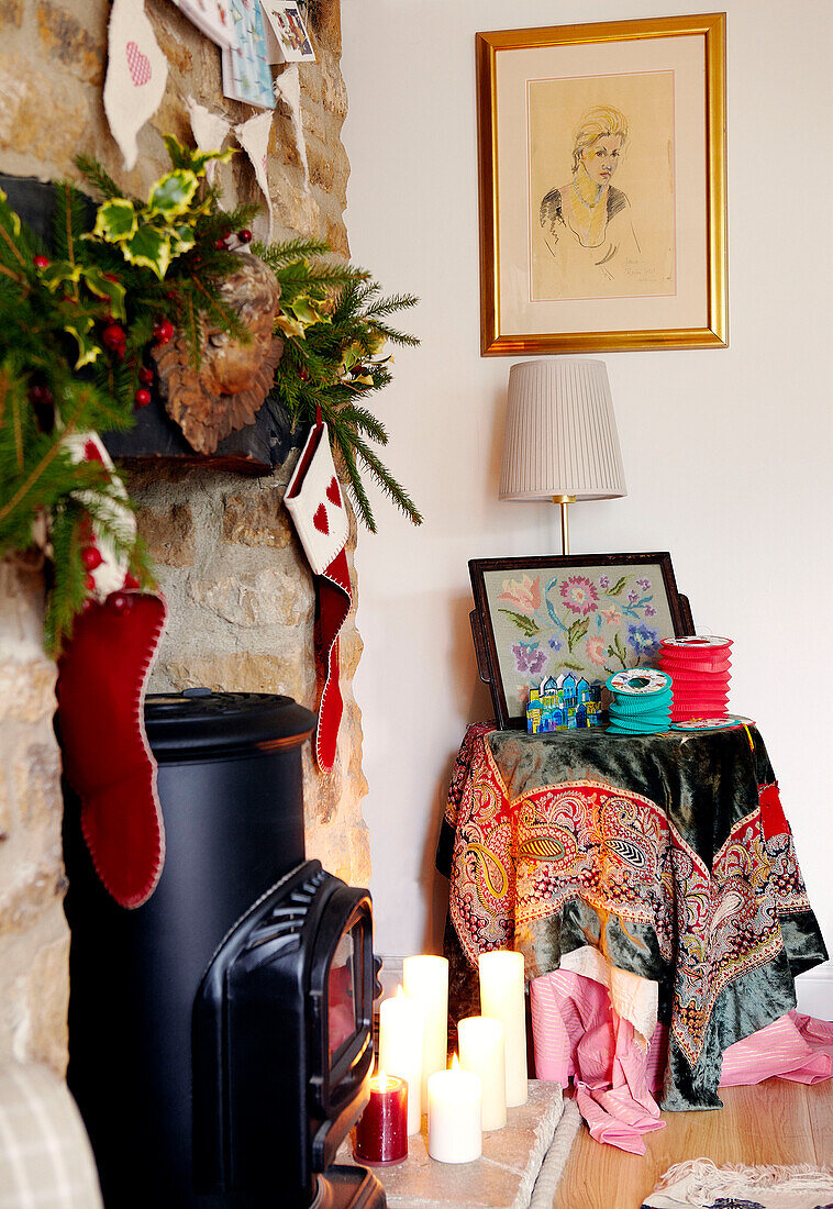 Christmas stockings hang over fireplace with cross stitch on side table