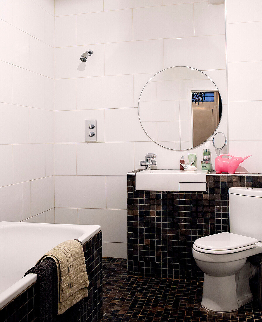 Black tiled bathroom with round mirror