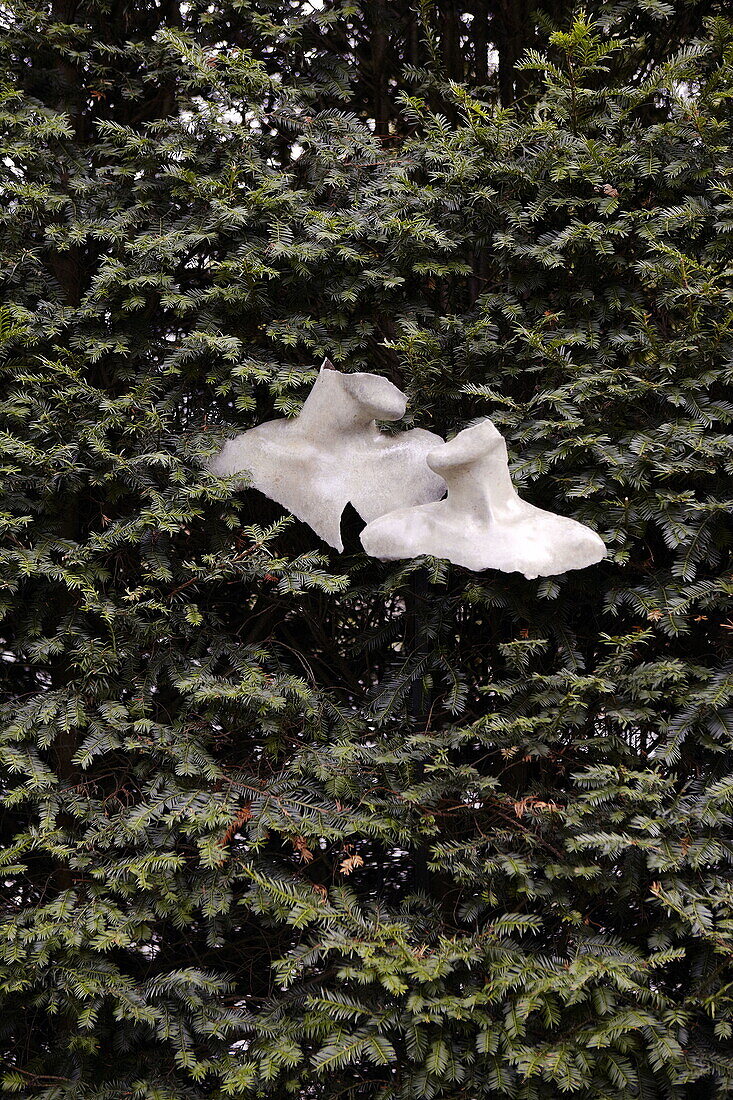 Fractured garden sculptures in evergreen tree The Cotswolds England UK