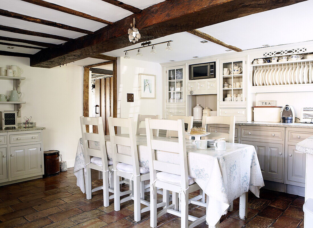 Table and chairs with fitted storage in beamed kitchen of Forest Row farmhouse conversion Surrey England UK