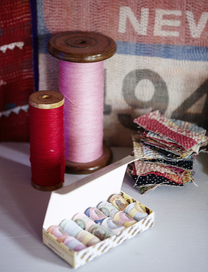 Rosa und rotes Garn auf alten Spulen mit Stoffmustern im Haus einer Londoner Textildesignerin UK