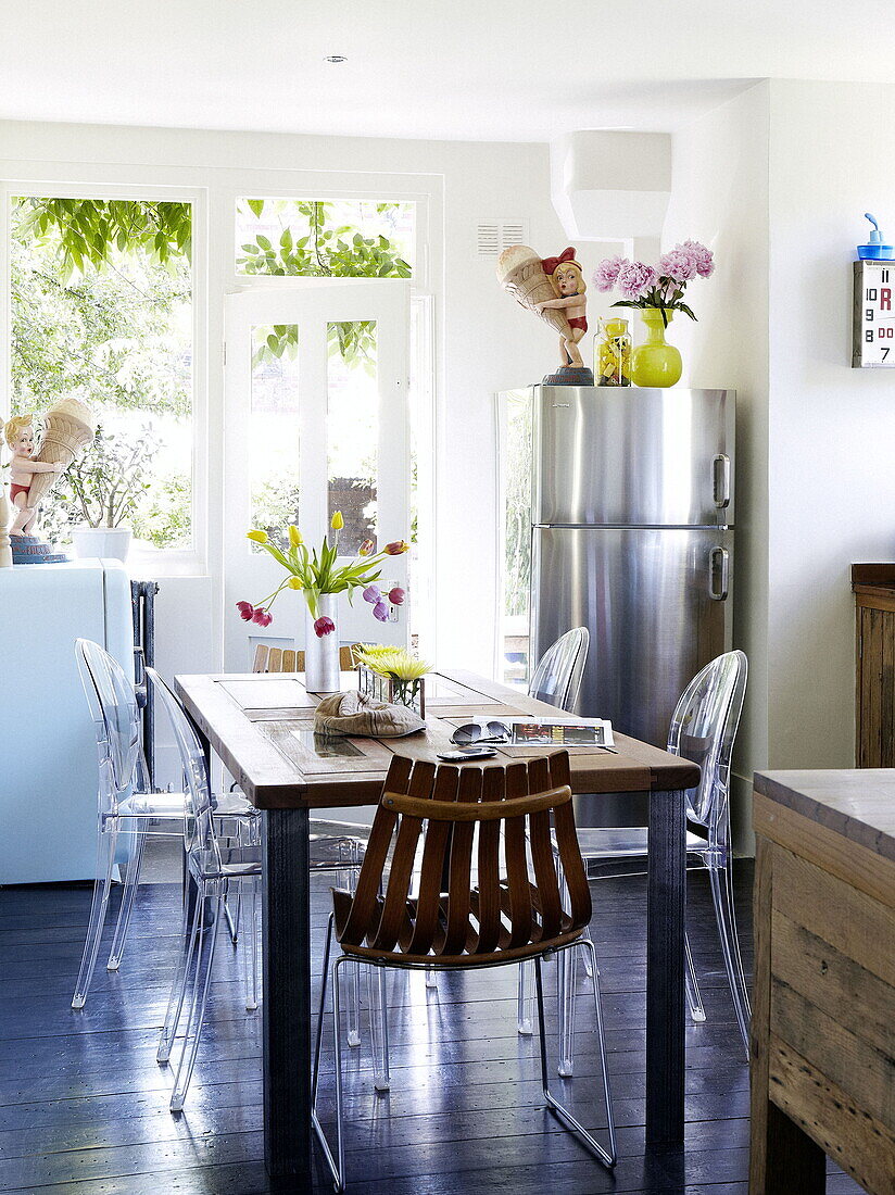 Edelstahl-Kühlschrank an der Hintertür der Küche mit Philippe Starck-Stühlen am Tisch in einem Londoner Einfamilienhaus, UK