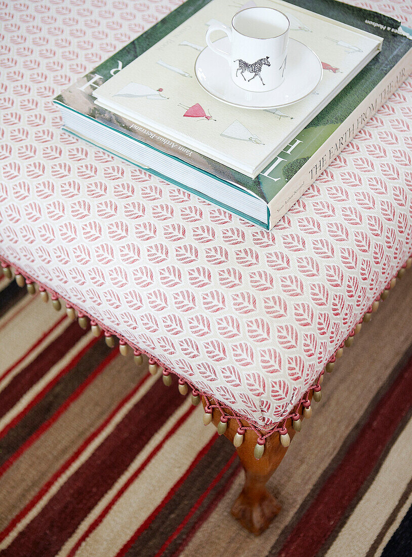 Cup and saucer with books on Ottoman in Oxfordshire home, England, UK