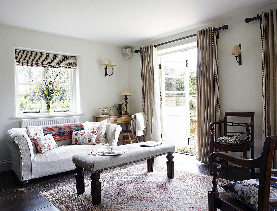 Upholstered footstool and dining chairs with sofa in living room of Oxfordshire home, England, UK