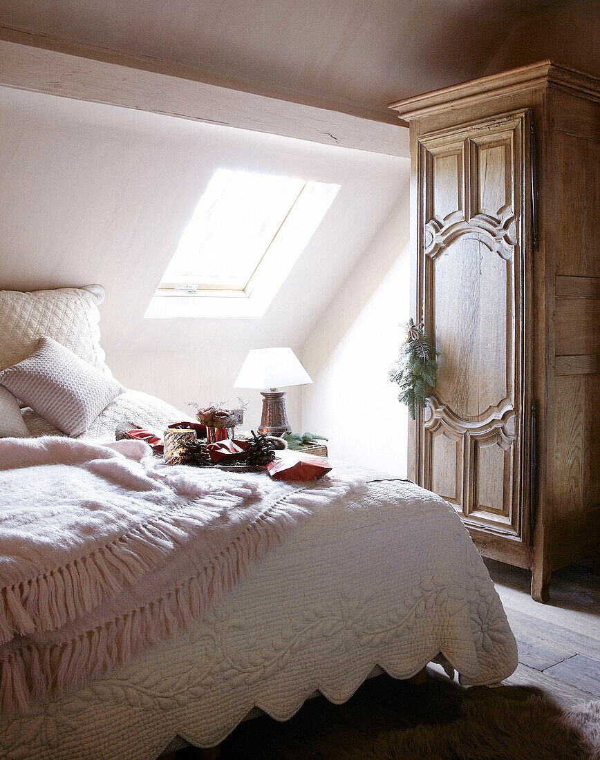 Sonnendurchflutetes Schlafzimmer im Dachgeschoss mit antikem Holzschrank in einem festlichen Haus in Oxfordshire, England, Vereinigtes Königreich