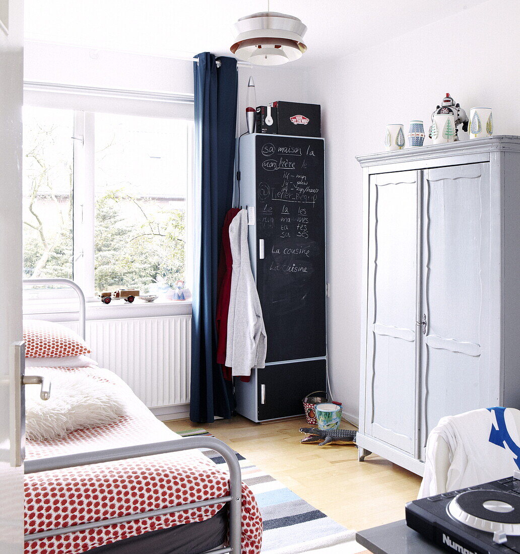 Hooded tops hang on wardrobe painted with blackboard paint in teenager's room in Bussum home, Netherlands