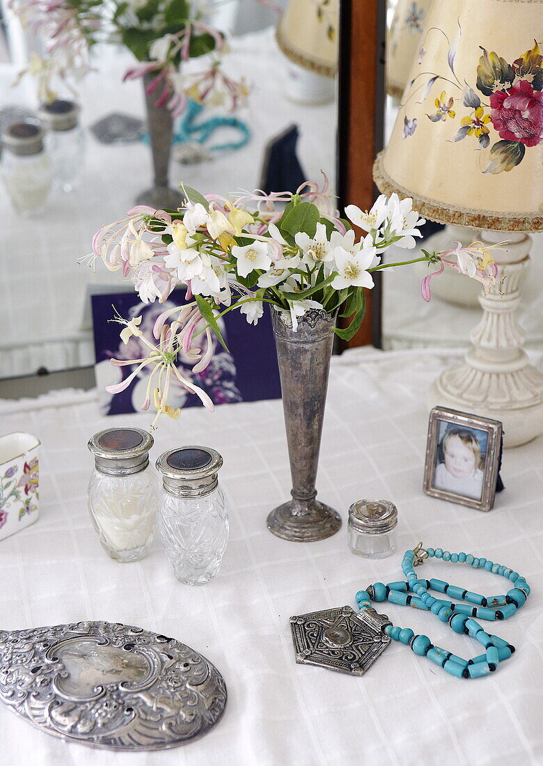 Cut flowers in silver vase with hand mirror on dressing table, Oxfordshire, England, UK