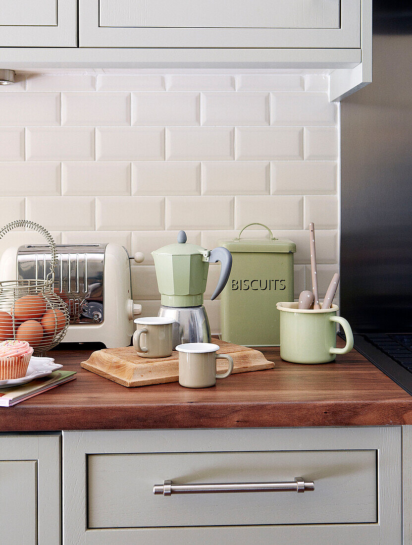 Cafetiere ad cups with toaster and egg basket on wooden kitchen counter in North London home, England, UK