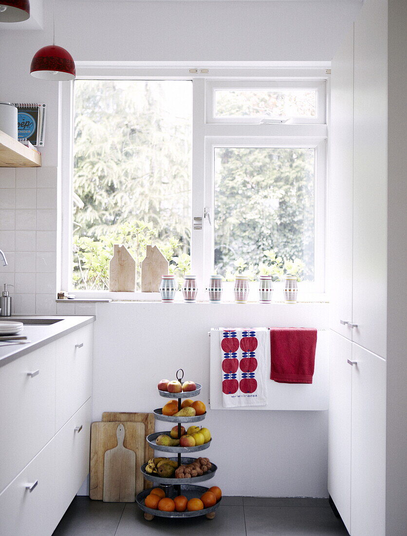 Essensstand und Schneidebretter am Fenster einer weißen Küche in einem Haus in Bussum, Niederlande