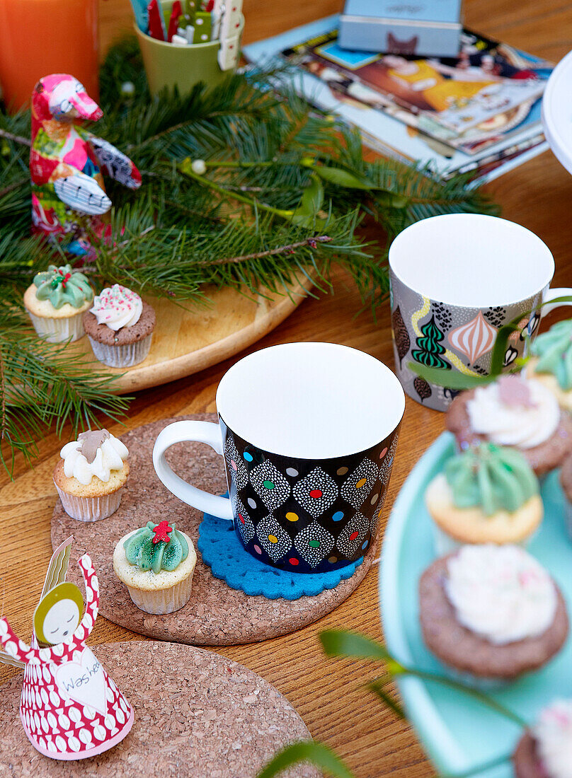 Cups and teacakes with pine needles on tabletop of London home England UK
