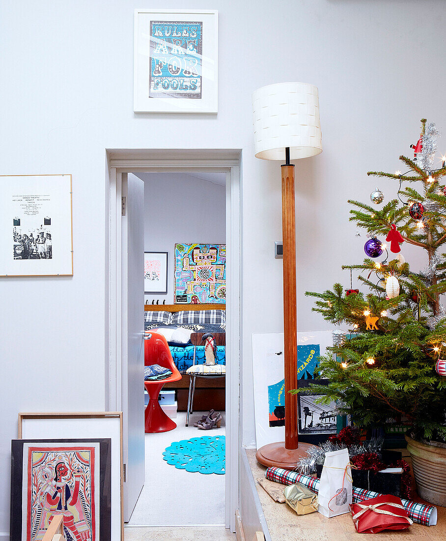 Christmas tree and lamp with view through doorway to bedroom of London family home England UK