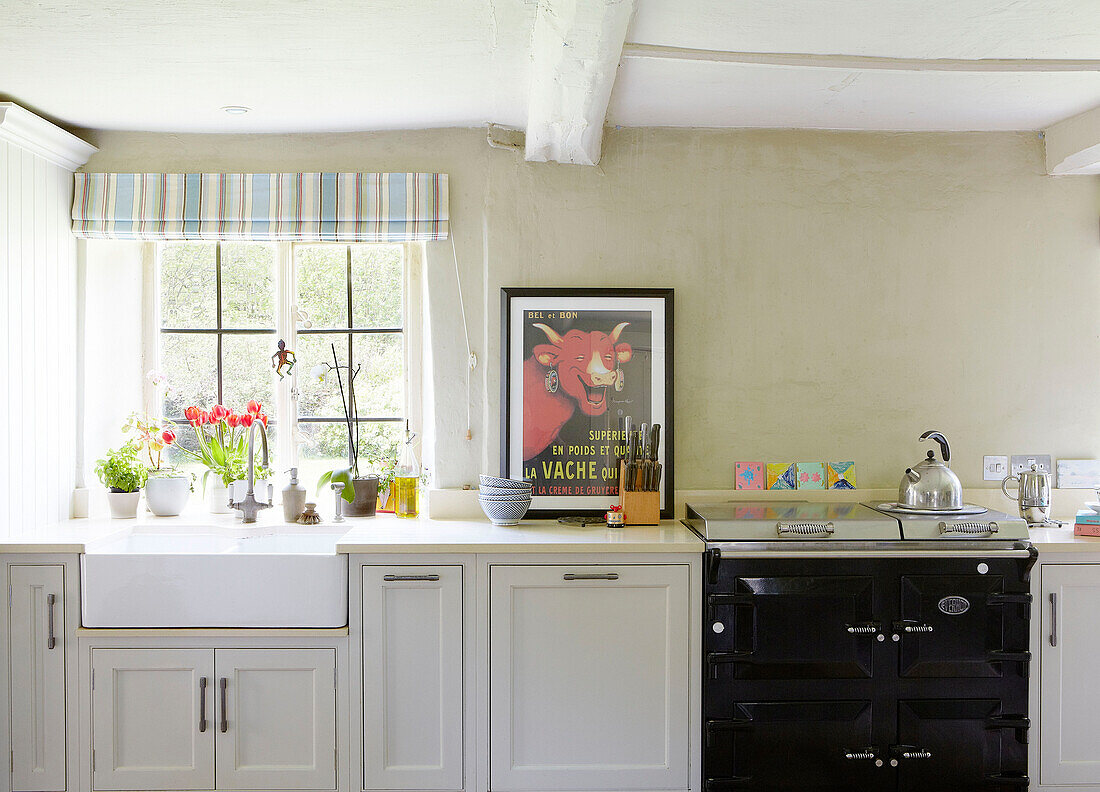 Silver kettle on hob of black range oven with Belfast sink in kitchen of Oxfordshire farmhouse England UK