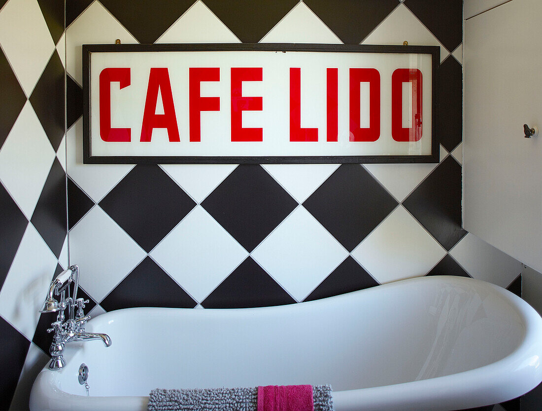 Schild mit der Aufschrift 'CAFE LIDO' an der karierten Wand über der freistehenden Badewanne in einem Familienhaus in Margate Kent England UK