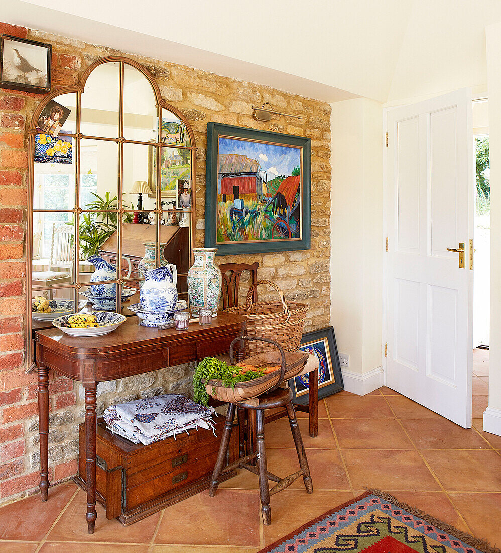 Mirror and side table in exposed brick entrance hall of Oxfordshire country house England UK