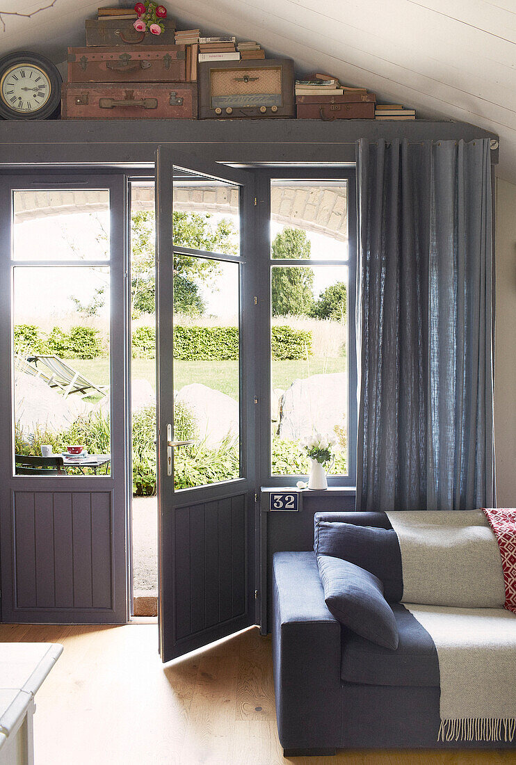 Blue painted door opening to garden from living room of Brittany schoolhouse conversion France