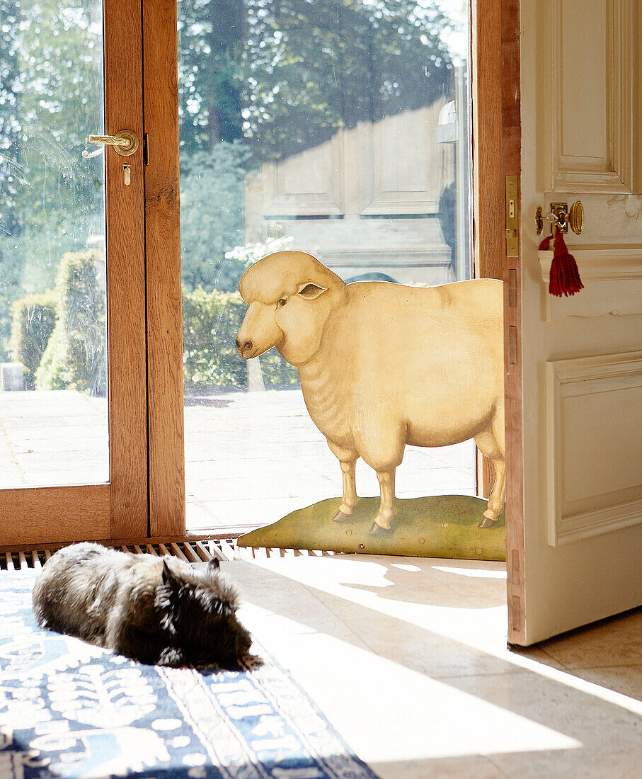 Hund schläft im Sonnenlicht neben einem aus Pappe ausgeschnittenen Schaf in einem traditionellen Landhaus Welsh Borders UK