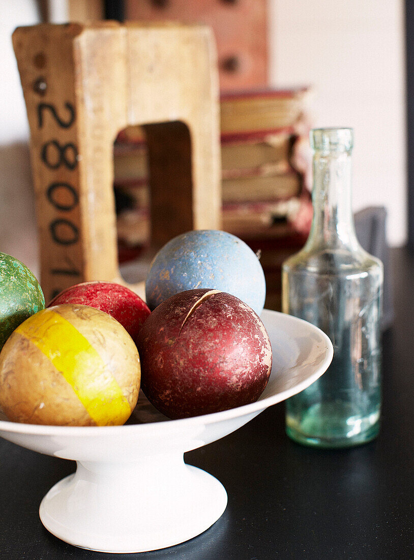 Croquet balls in fruit bowl with glass bottle in Brittany farmhouse France