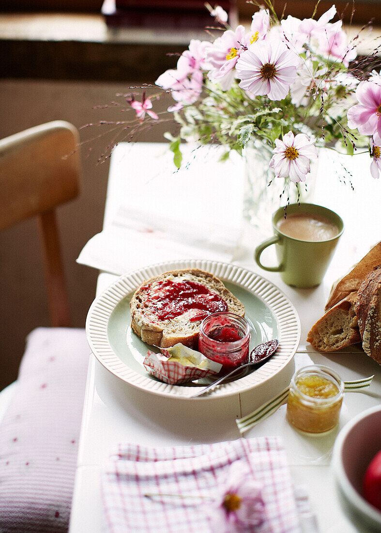 Jam and bread with cut flowers on breakfast table in Brittany cottage France