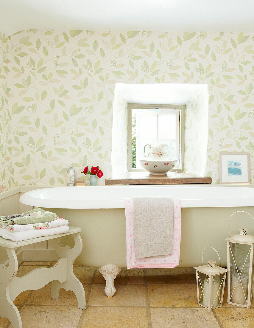 Freistehende Badewanne unter dem Fenster mit Blattmustertapete in Devonshire cottage UK