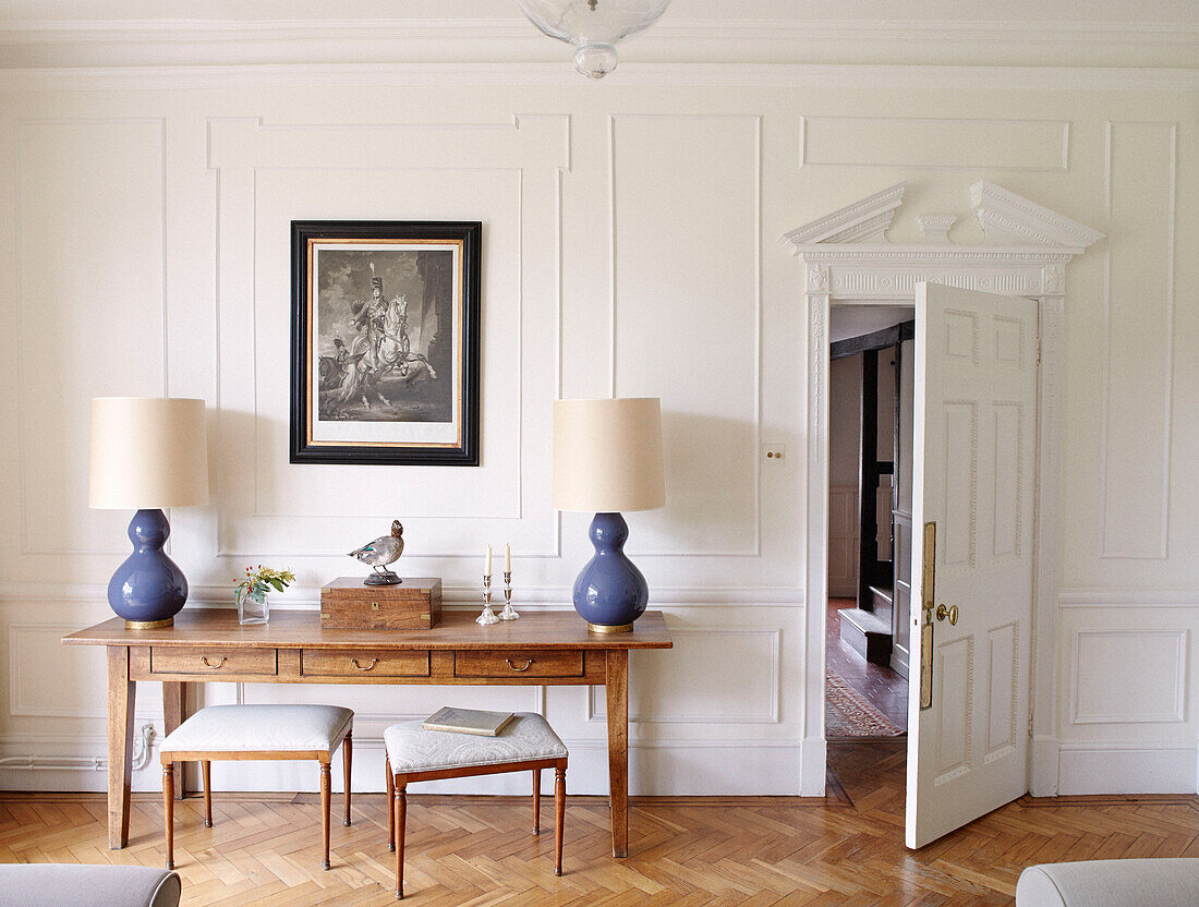 Stools at wooden table with blue matching lamp bases in panelled Bicester drawing room Oxfordshire England