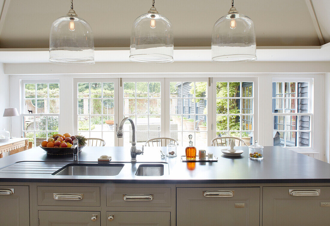 Fruit bow on kitchen island with double sink and view through patio doors to garden of Buckinghamshire home UK