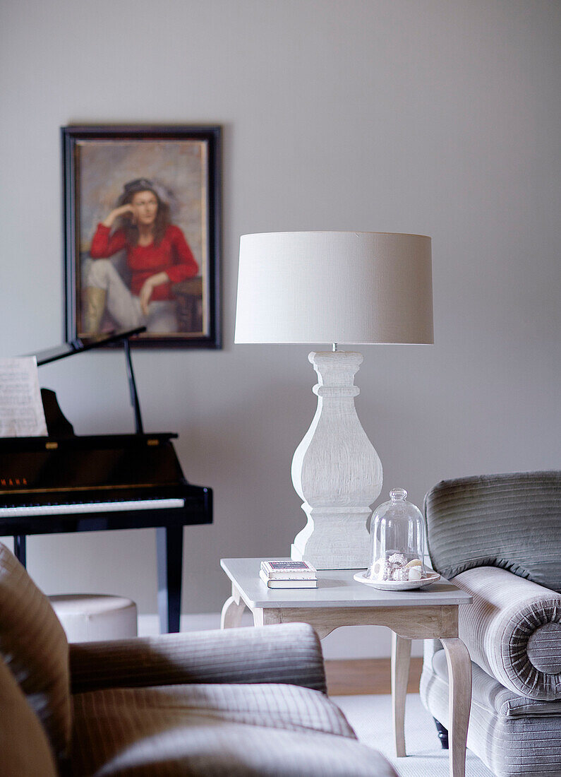 Cremelampe auf Beistelltisch mit Klavier und gerahmtem Porträt in einem Haus in Buckinghamshire, UK