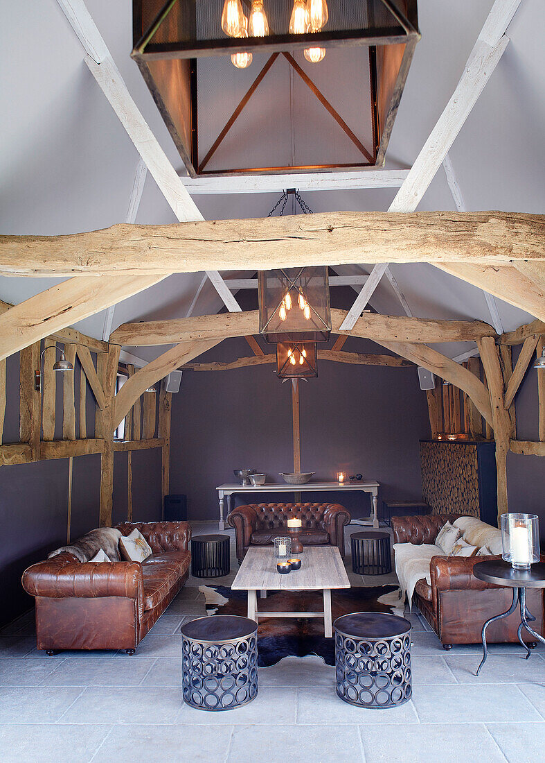 Braune Ledersofas in einem Wohnzimmer in einer umgebauten Scheune in Buckinghamshire, Großbritannien