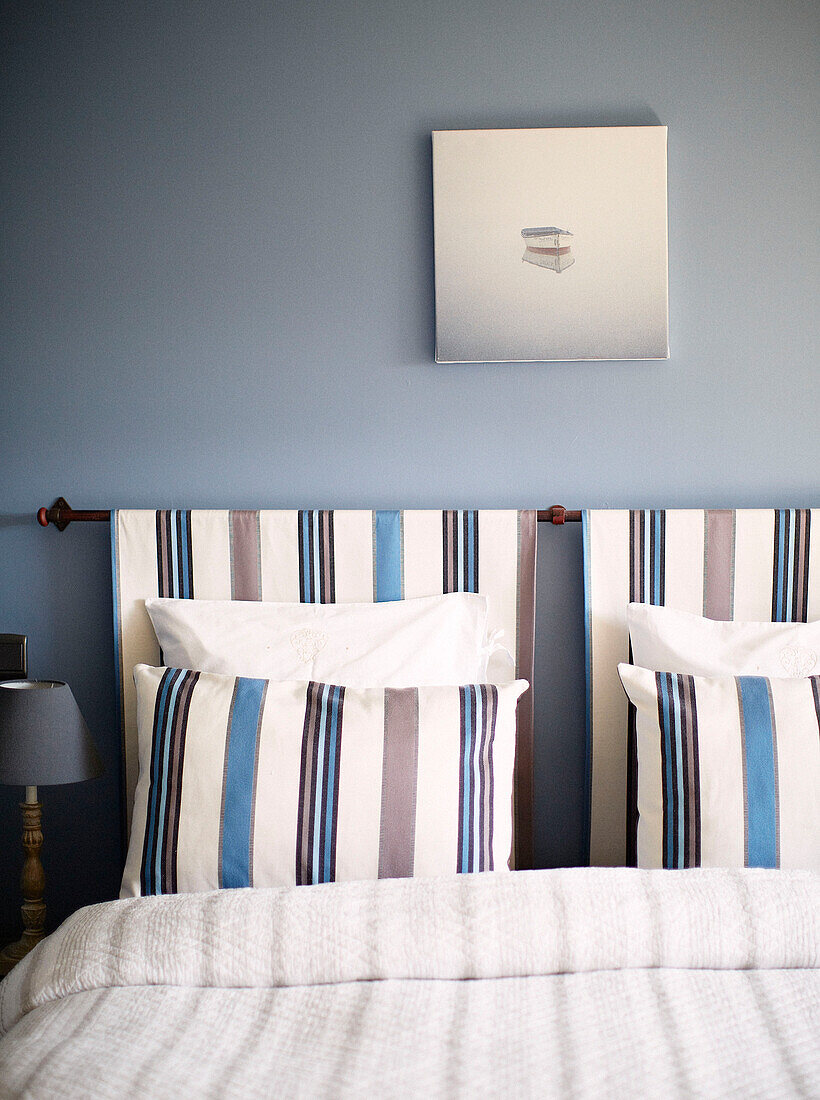 Co-ordinating headboard with striped pillows in light blue bedroom of Brittany guesthouse France