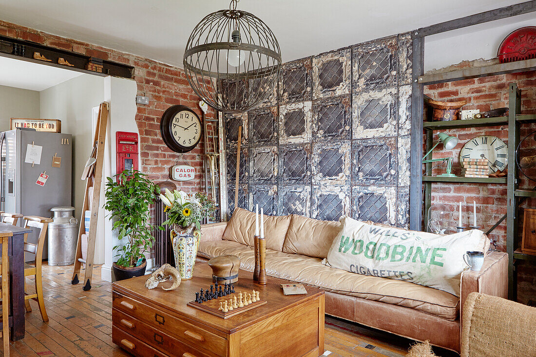 Braunes Ledersofa und Metallpendel im Wohnzimmer mit industrieller Wandgestaltung in einem Haus in Sunderland, Tyne and Wear, England UK