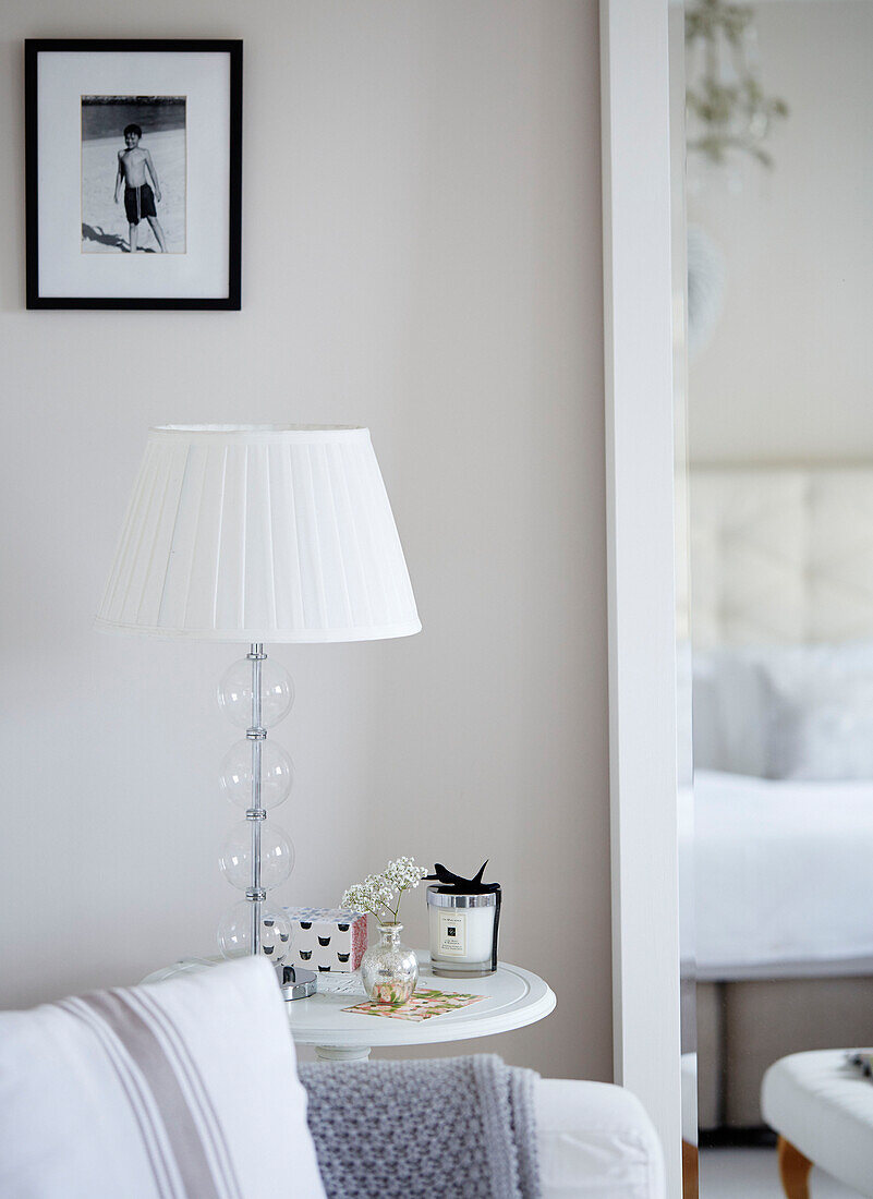 Lamp and cut flowers with scented candle on side table in York townhouse England UK