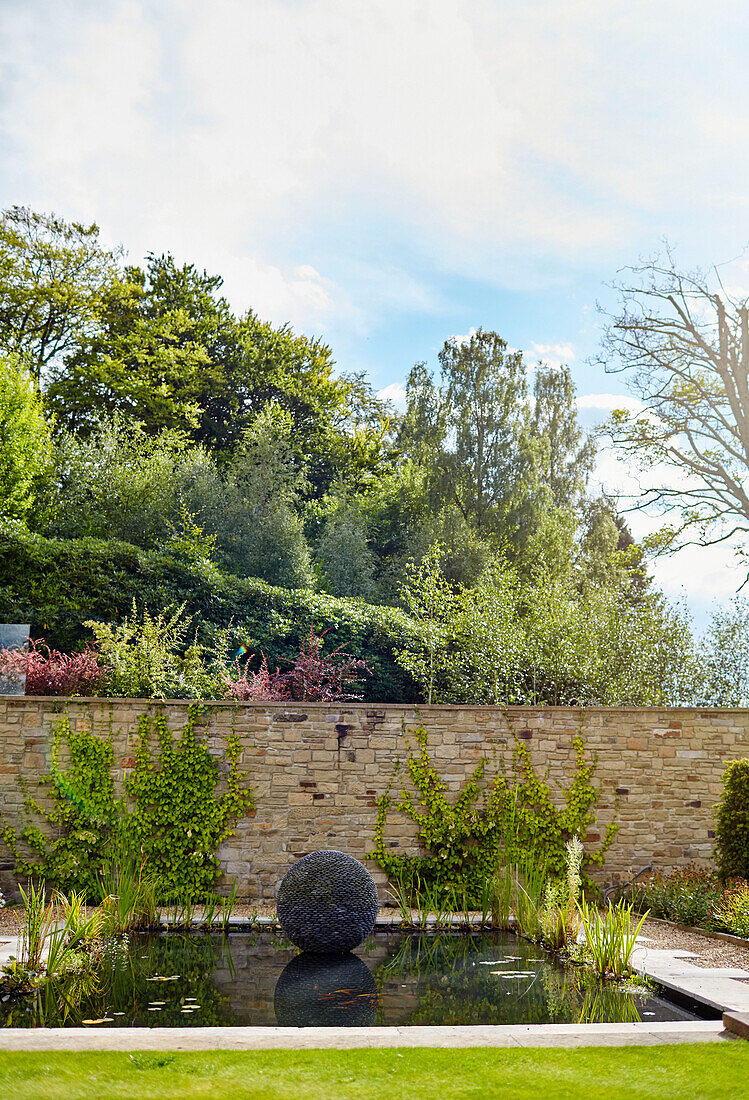 Garden ornament in pond of detached 19th century stone-built house Northumberland, UK