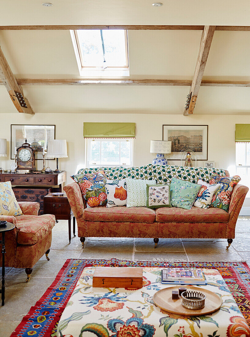 Armchair and sofa with assorted cushions and tug in attic conversion of Hexham farmhouse Northumberland UK