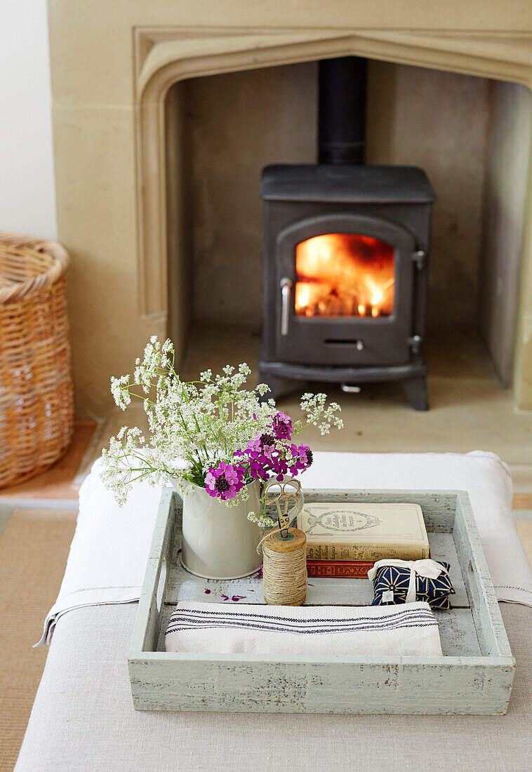 Schnittblumen auf einem Tablett mit beleuchtetem Holzofen in einem Haus in Northumbria, England, UK