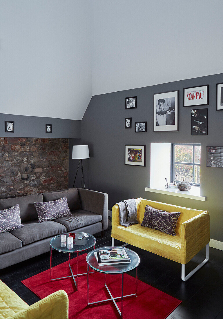 Yellow armchair with glass-topped side tables and framed prints in 19th Century Grain Mill conversion Scottish Borders, UK