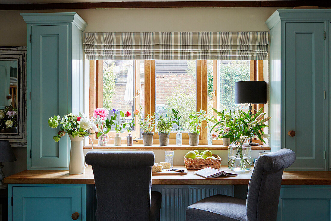 Ein Paar graue Stühle am Schreibtisch unter dem Fenster und hellblaue Einbauschränke in einem Haus in Kent England, UK