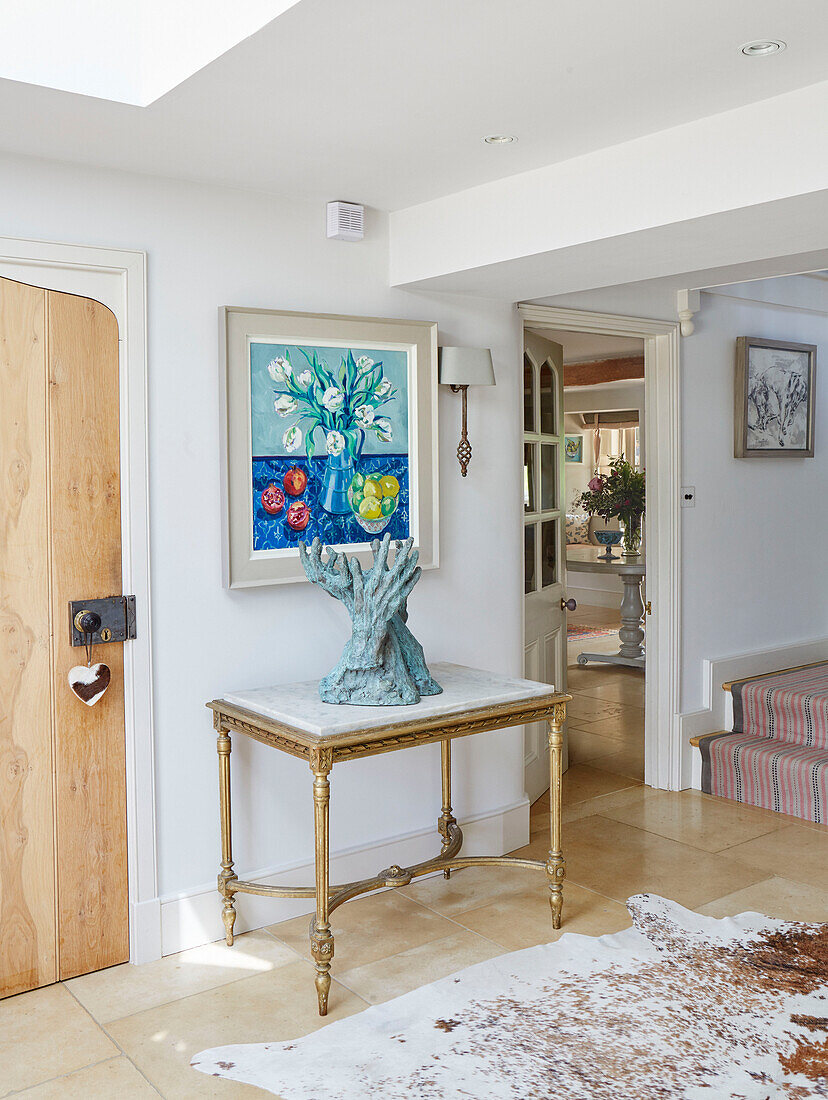 Modern artwork and sculpture on side table in entrance all of Warwickshire farmhouse, UK